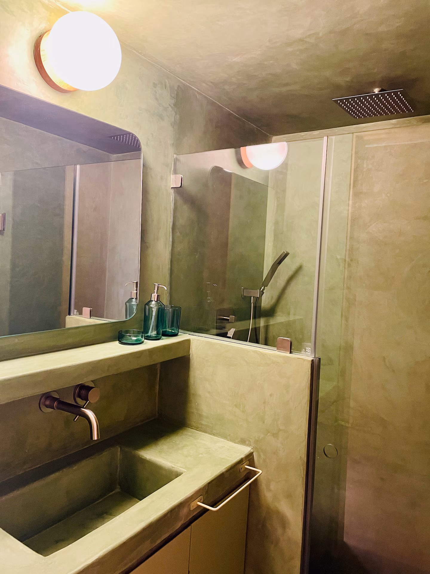 Bathroom with green concrete sink and rainfall shower