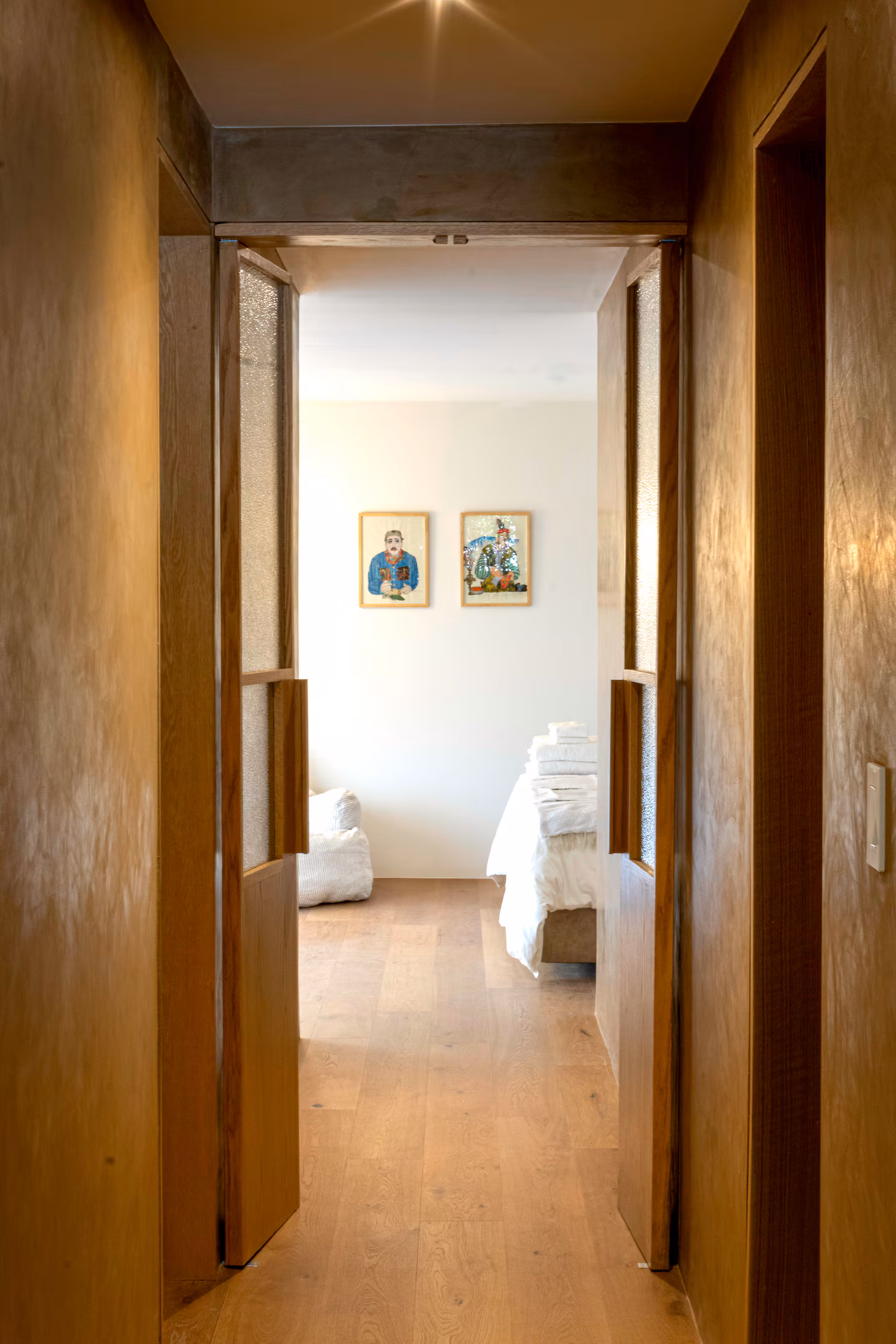 Hallway view showing bedroom doors and wood floors