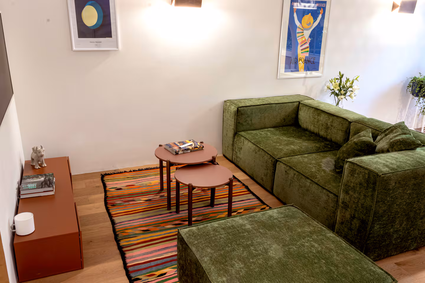 Living room with green velvet sofa and colorful Mexican rug